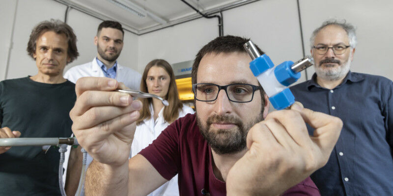 Daniel Knez holds a sample of the battery material with tweezers. In the backgro